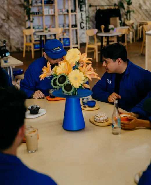 Guests around the communal table with flowers on it
