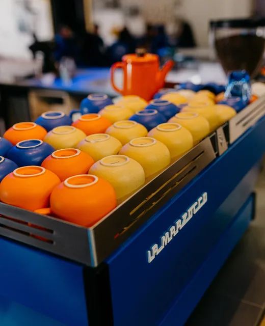 Orange and blue cups warming on top of the espresso machine