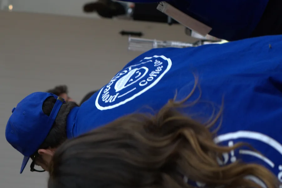 A Provecho barista in a branded jacket working an AeroPress at a competition bench