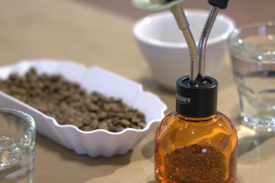 An aroma kit bottle and dropper beside a bowl of whole beans