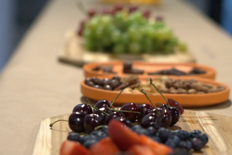 Wooden boards of blackberries, strawberries and grapes laid out for tasting